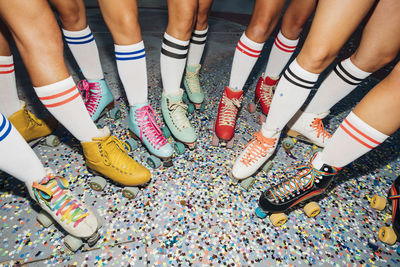 Legs of women wearing roller skates over confetti