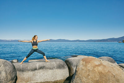 Young woman practicing yoga on lake tahoe in northern california.