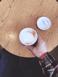 High angle view of hand holding coffee cup on table