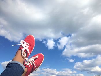 Low angle view of person holding heart shape against sky