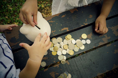 Midsection of children putting coin in piggy bank