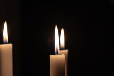 Close-up of lit candle in darkroom
