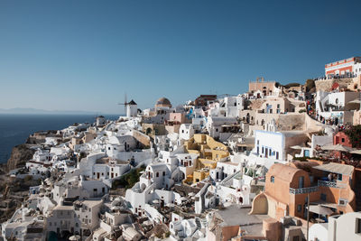 Aerial view of townscape by sea against clear blue sky