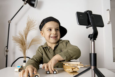 Adorable, cute, little boy blogger recording lifestyle blog, talking to camera of smartphone 