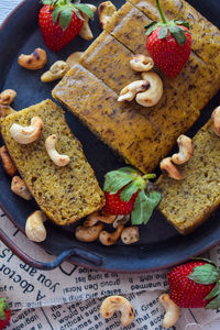 Close-up of high angle sliced banana cake with topping strawberry and cashew nuts
