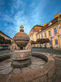 Fountain in city against sky