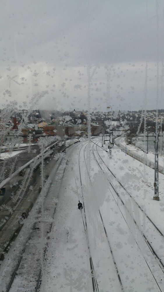 snow, winter, cold temperature, season, weather, transportation, railroad track, wet, covering, frozen, sky, road, white color, day, the way forward, no people, power line, high angle view, built structure, nature