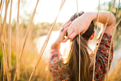 Woman tying hair against plants