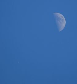 Low angle view of half moon against blue sky at night