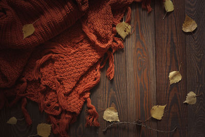 Cozy autumn background with knitted sweater scarf on a wooden background, with yellow birch leaves