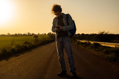 Full length of man using mobile phone on road