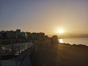 People on beach against clear sky during sunset