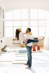 A young couple in love have moved into a new house and are making repairs painting white walls