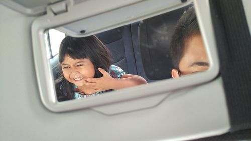 Reflection of father and daughter on rear-view mirror in car