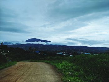 Scenic view of road by mountains against sky