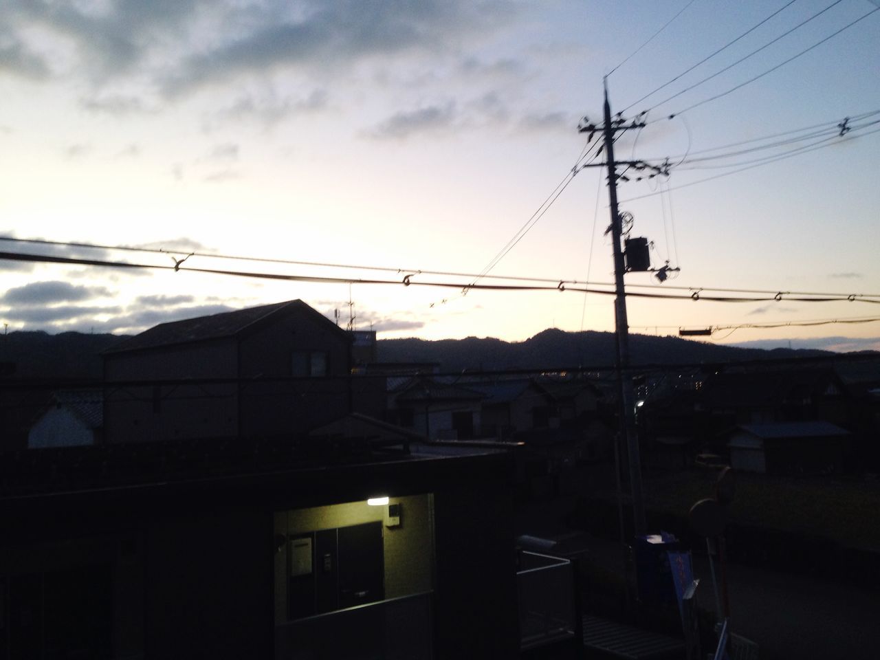 power line, building exterior, electricity pylon, cable, architecture, built structure, electricity, power supply, sky, house, residential structure, residential building, power cable, town, sunset, city, fuel and power generation, street light, cloud - sky, technology