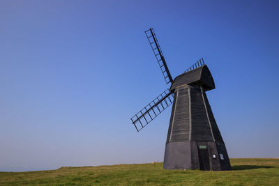 Traditional windmill on field against clear sky