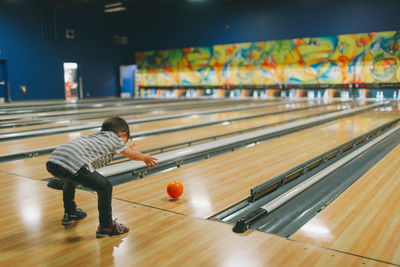 Boy playing bowling ball at mall