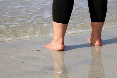 Low section of man standing on beach