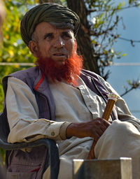 Mature bearded man looking away while sitting on chair