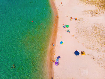 Aerial view of sandy beach with tourists swimming in beautiful clear green sea water