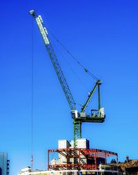 Low angle view of crane against blue sky