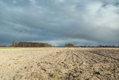 Dark rain clouds over a plowed field, spring rural view