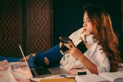 Woman holding mobile phone while sitting on table