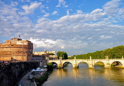 Arch bridge over river against cloudy sky