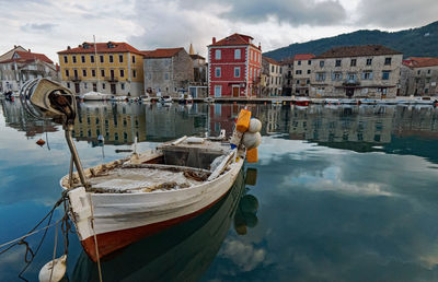 Nautical vessel moored on sea against buildings in city