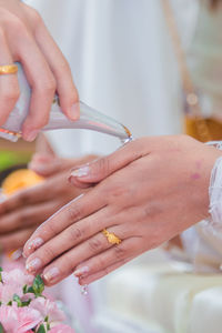 Cropped image of person pouring water on clasped hands