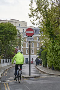Rear view of man riding bicycle on street