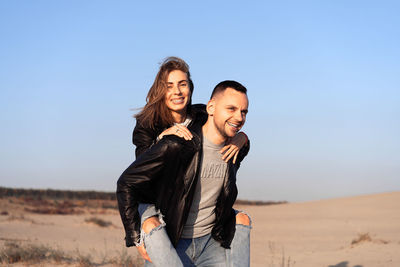 Young man giving his girlfriend a piggyback ride