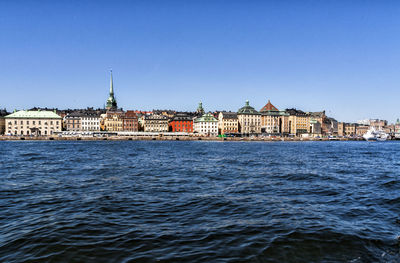 River by buildings against clear blue sky at strandvagen