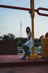 Portrait of smiling woman leaning against pole