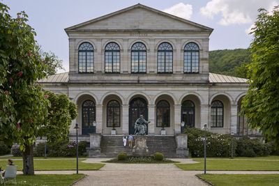 Statue by historic building against sky