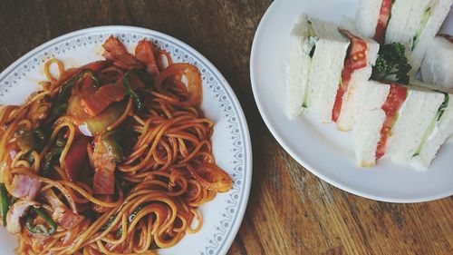 Directly above shot of sandwiches and noodles in plates on table