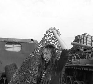Portrait of smiling young woman standing against sky