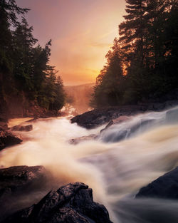 Scenic view of waterfall at sunset