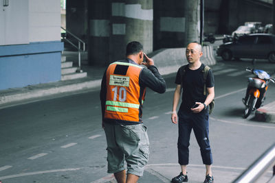 Rear view of people walking on road in city