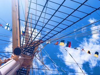 Low angle view of flags hanging against cloudy sky