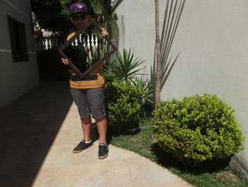 Portrait of boy holding mirror with reflection of trees and railing