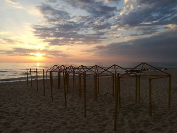 Lifeguard hut on beach against sky during sunset