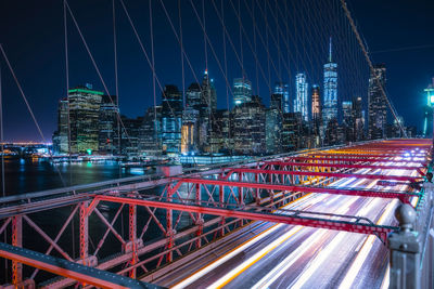 Light trails on bridge against sky at night