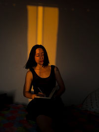 Portrait of young woman sitting on bed at home