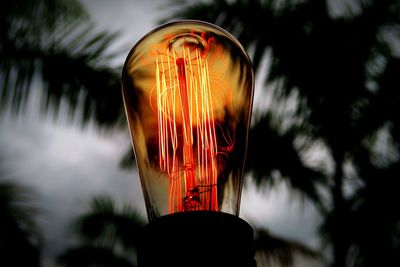 Low angle view of illuminated light bulb against sky at night