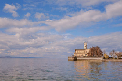 Building by sea against cloudy sky