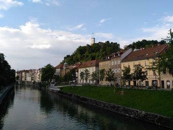 River by houses and buildings against sky