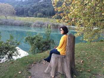 Rear view of woman sitting on tree