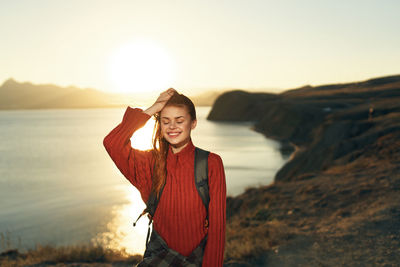 Woman standing at beach against sky during sunset